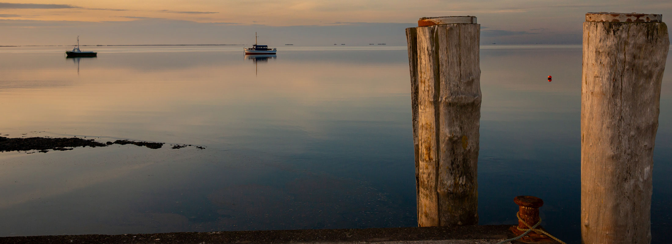 Stille Nordsee mit zwei Booten und die Halligwelt am Horizont lädt zum Verweilen und Erholen ein