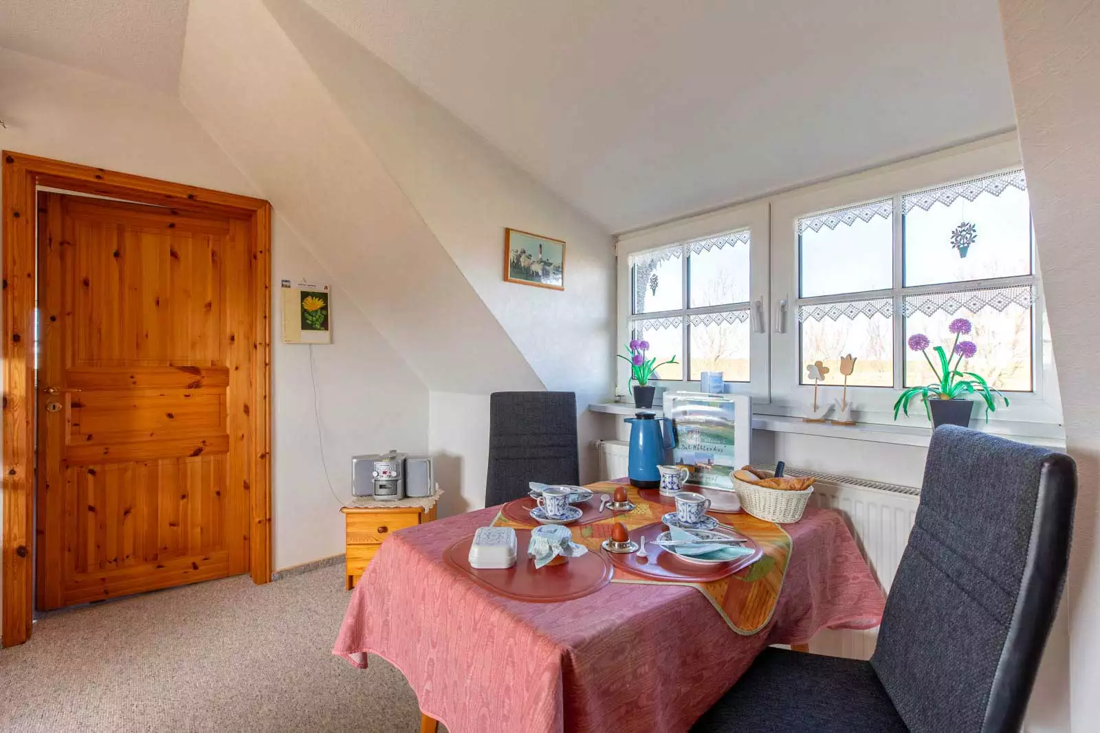 Essplatz mit gedecktem Frühstückstisch und Blick aus dem Fenster ins Grüne in der Ferienwohnung Deichgraf