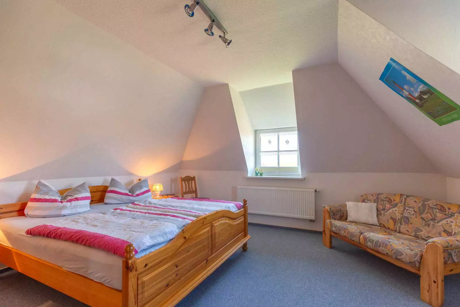 Schlafzimmer mit Doppelbett und Couch in der Ferienwohnung Deichgraf