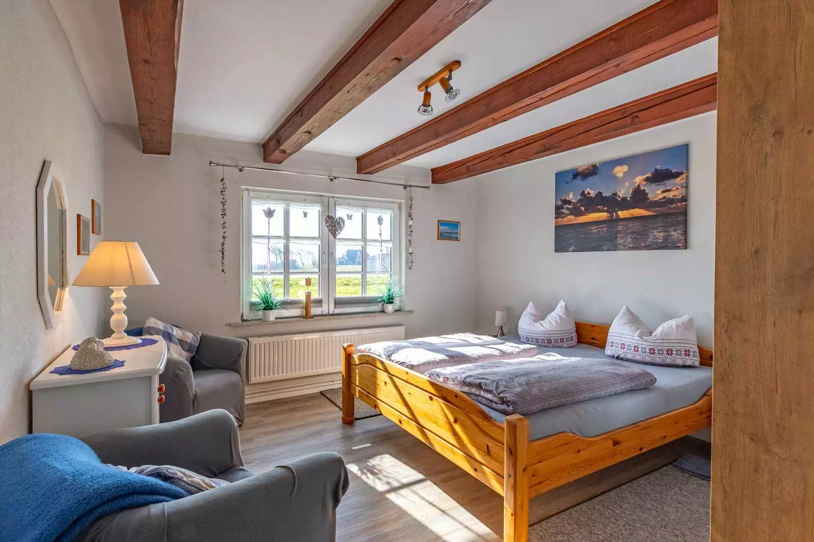 Schlafzimmer mit Doppelbett und zwei Sesseln in der Ferienwohnung Höck Hallig