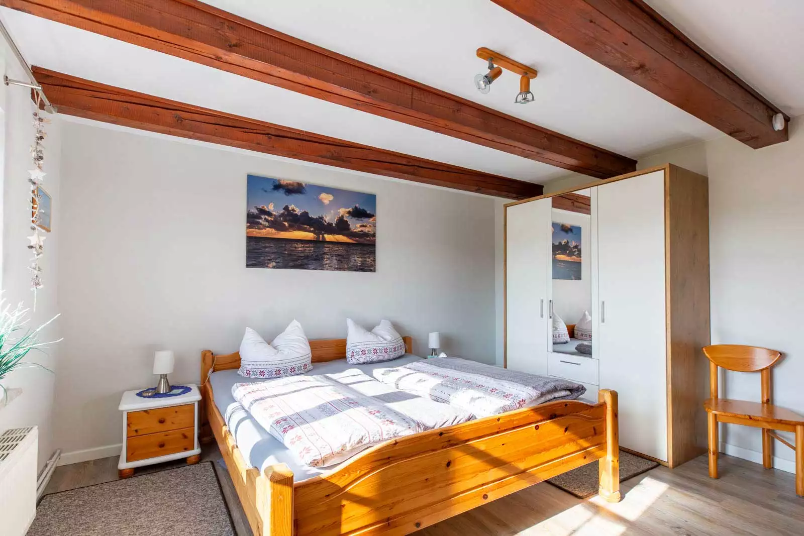 Gemütliches Schlafzimmer mit Doppelbett und sonnigem Fensterblick ins Grüne.