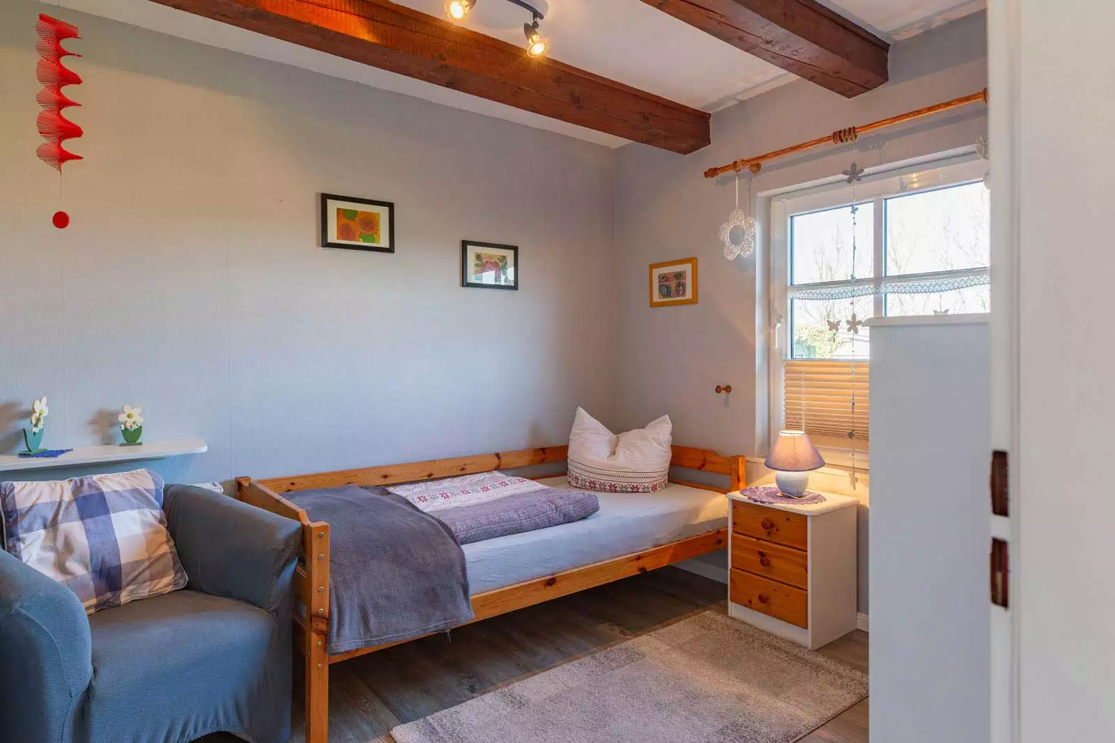 Schlafzimmer mit Einzelbett, Sessel und Fenster zum Garten in der Ferienwohnung Höck Hallig