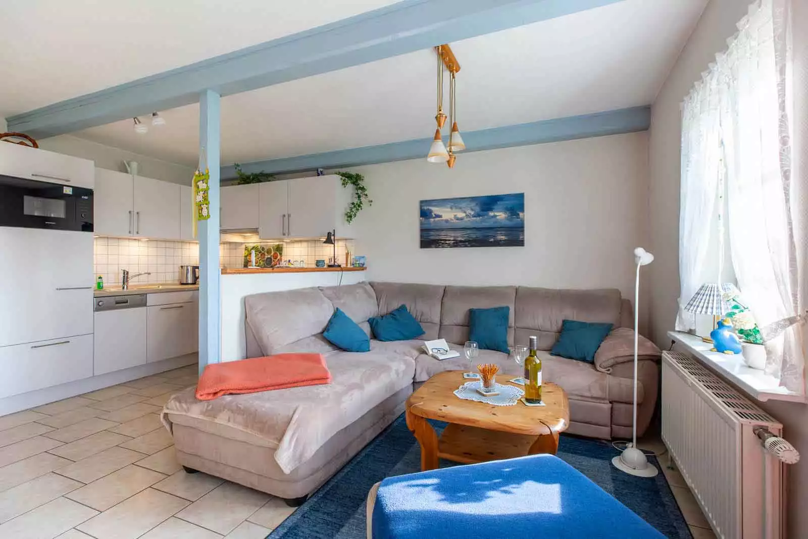 Gemütliche Couchecke im Wohnzimmer der Ferienwohnung Schimmelreiter mit Küche im Hintergrund