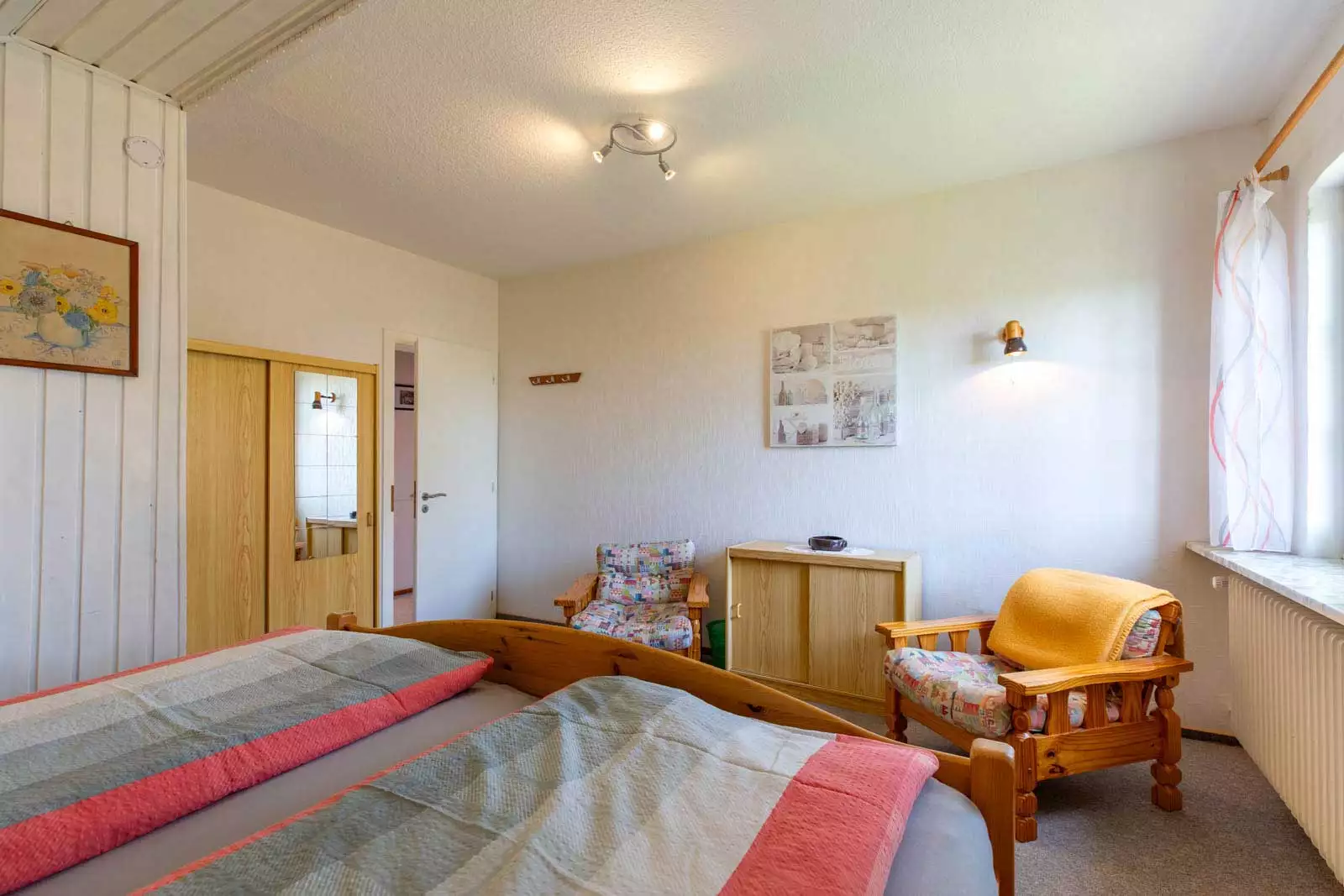 Schlafzimmer mit Doppelbett, Kleiderschrank und Sitzbereich in der Ferienwohnung Morgensünn