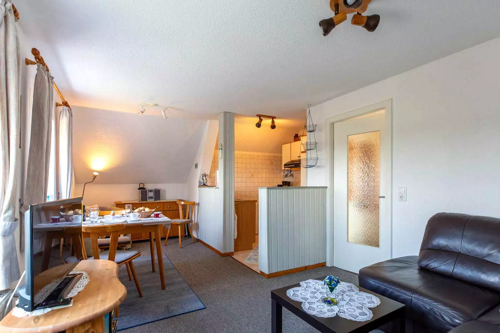 Wohnraum der Ferienwohnung Abendsünn mit Couchecke, Essplatz und kleiner Küche