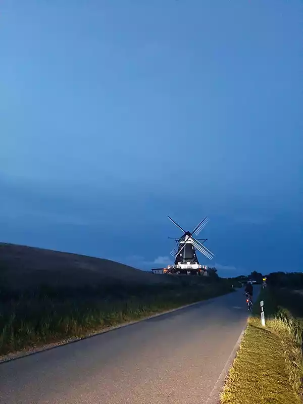 Deich und Nordermühle auf Pellworm in der Abendstimmung unter dramatischem Himmel