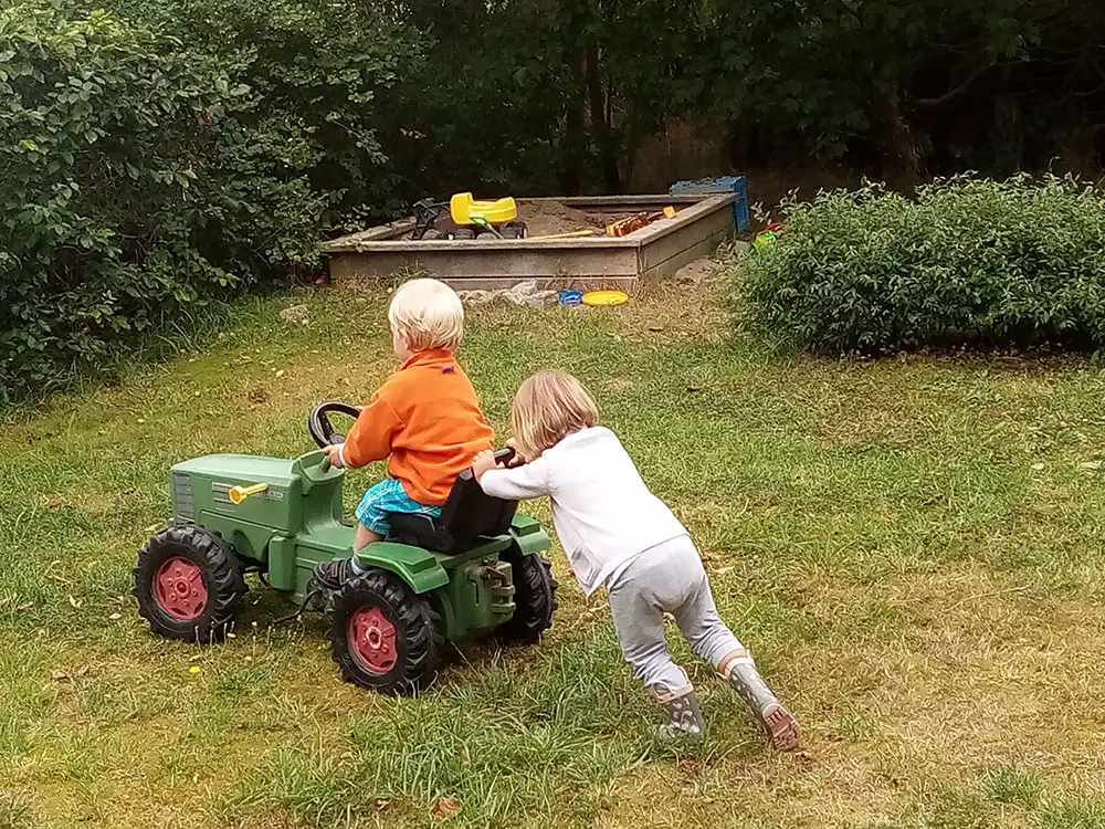 Kinder spielen mit einem kleinen Trecker auf dem Bauernhof auf Pellworm