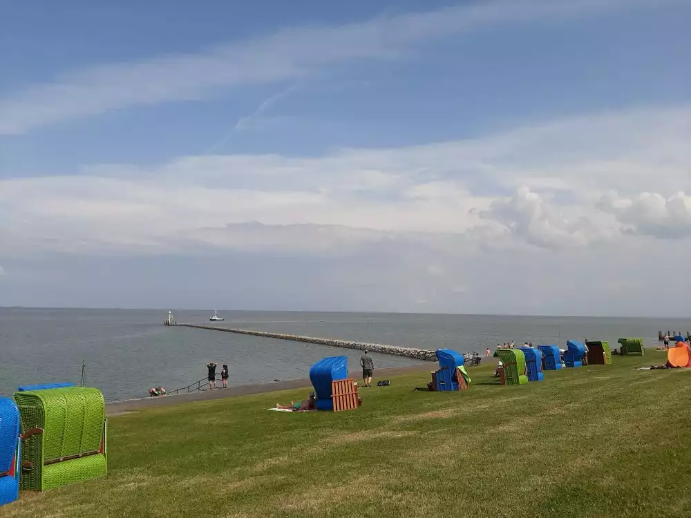 Grüner Deich mit Strandkörben und Familien beim Baden in der Nordsee auf Pellworm