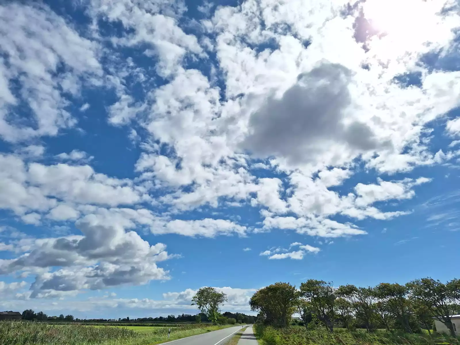 Leere Straße auf Pellworm unter weitem blau-weißem Himmel mit typischen norddeutschen Wolken