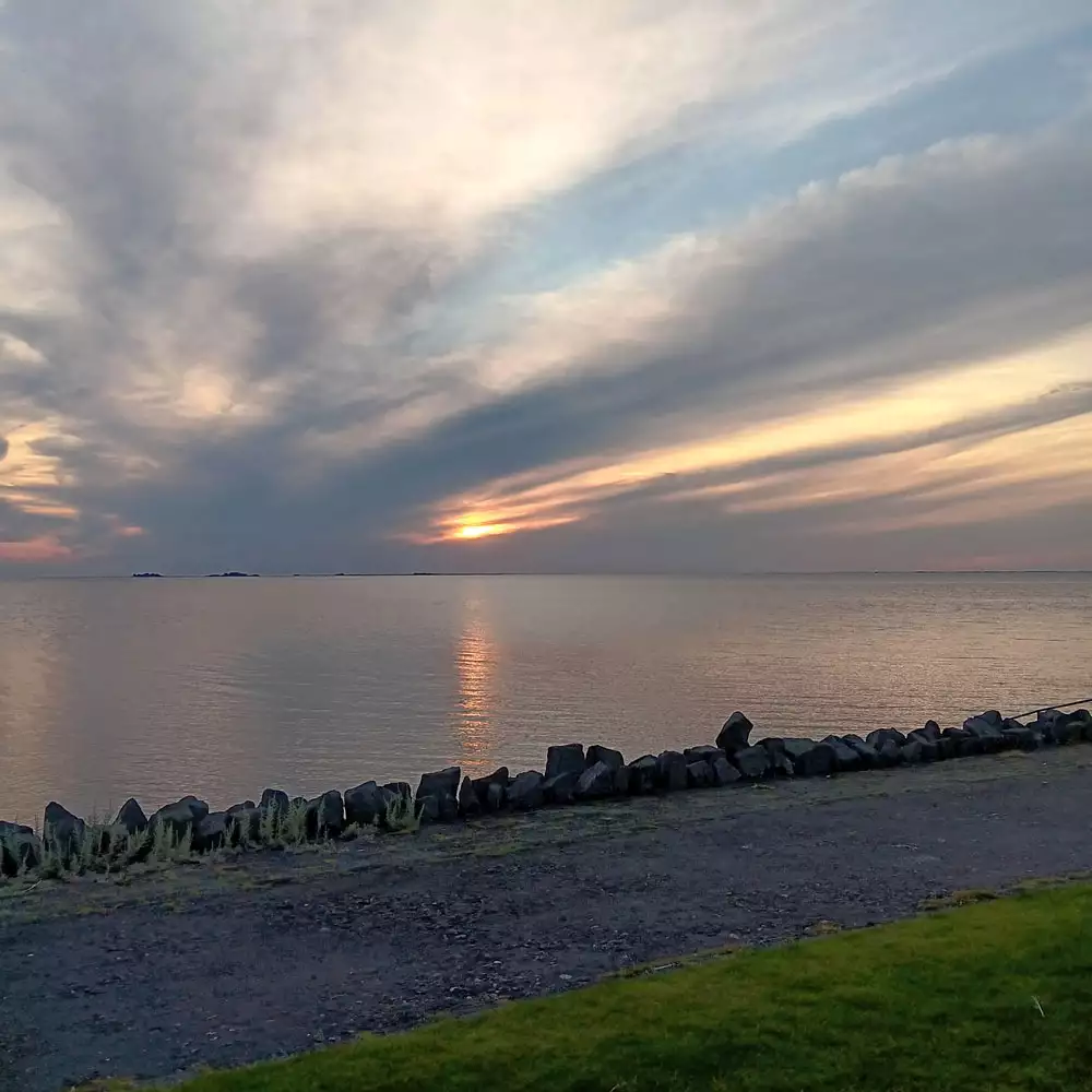 Abendstimmung am Außendeich von Pellworm mit Sonnenuntergang, Nordsee und betoniertem Inselweg.