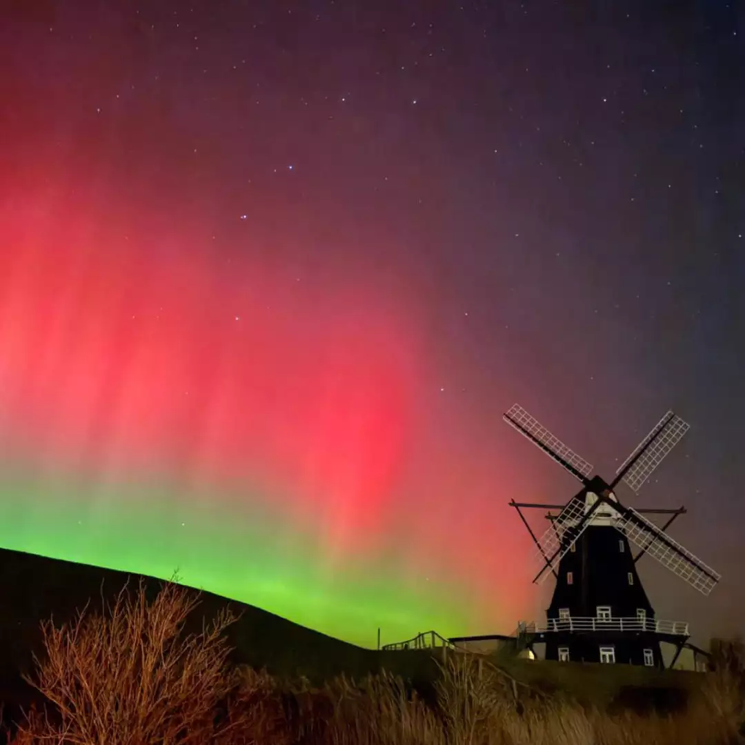 Nordermühle auf Pellworm bei Nacht mit seltenen Polarlichtern am Himmel.