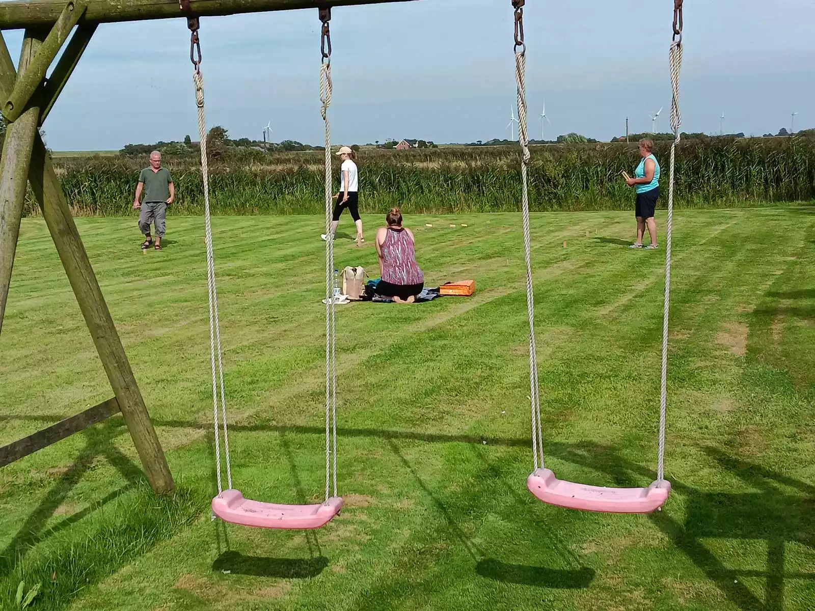 Garten des Dat Möhlenhus mit Wiese, Schaukeln und spielender Familie an einem sonnigen Nachmittag