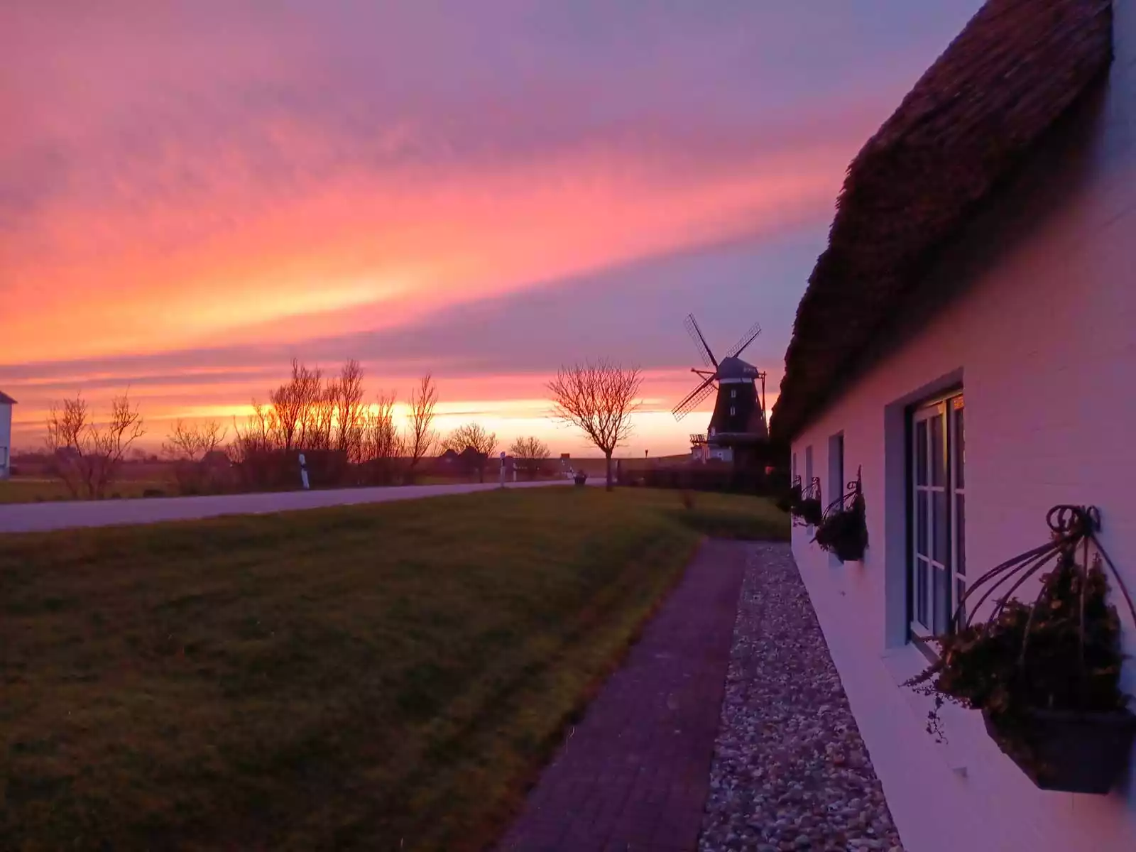 Dat Möhlenhus im Sonnenuntergang mit Blick zur Nordermühle unter farbigem Abendhimmel