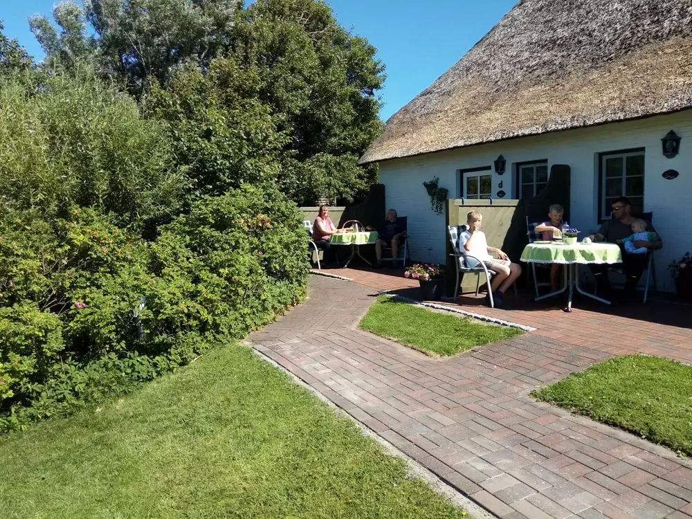 Die Rückseite des Hauses mit separaten Eingängen, Terrassen und dem frisch gedeckten Reetdach.